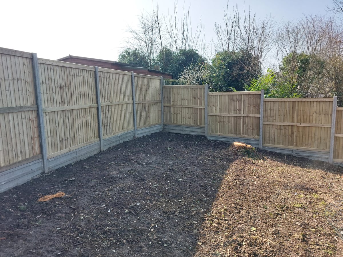 New fence panels and concrete posts enclosing a cleared garden corner