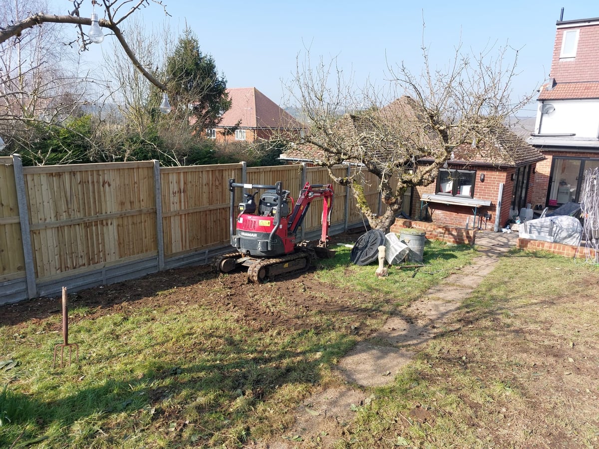 New timber boundary fencing beside a garden digger during landscaping work