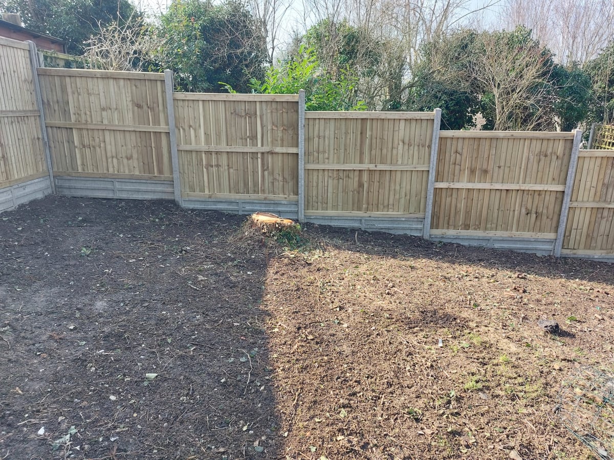 Finished fence panels and concrete gravel boards around a cleared garden